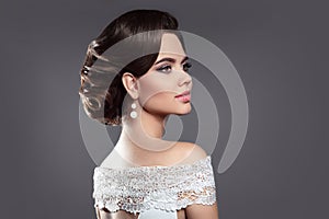 Retro woman brunette beauty portrait. Elegant lady with hairstyle and makeup, pearl earrings jewelry posing isolated on studio gr