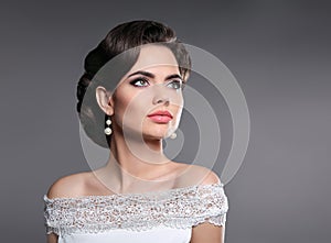 Retro woman portrait. Elegant lady with hairstyle, pearls jewelry set posing isolated on studio gray background.
