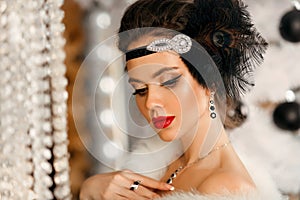 Retro woman in white fur coat. Cristmas portrait. Elegant lady with feather in wedding hairstyle, beauty makeup and diamond black