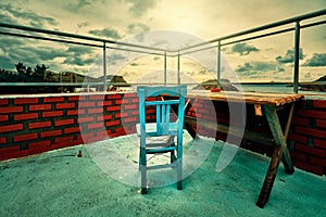 Retro wooden blue chair and a wooden table on the balcony with red brick walls