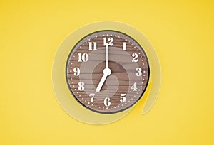 The Retro wooden clock at 7 O\' clock on yellow color background