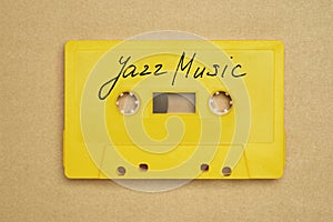 Retro yellow audio cassette tape with jazz music laying on the paper background.