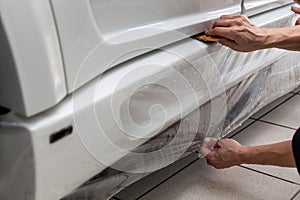 Retrofitting the car with a solid transparent protective film, the master glues the coating protecting the vehicles from scratches