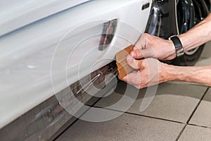 Retrofitting the car with a solid transparent protective film, the master glues the coating protecting the vehicles from scratches