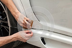 Retrofitting the car with a solid transparent protective film, the master glues the coating protecting the vehicles from scratches