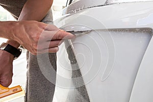 Retrofitting the car with a solid transparent protective film, the master makes an incision with a knife on the coating protecting