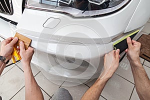 Retrofitting the car with a solid transparent protective film, the master smooths the surface by squeezing air bubbles with a