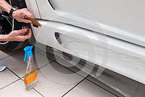 Retrofitting the car with a solid transparent protective film, the master smooths the surface by squeezing air bubbles with a