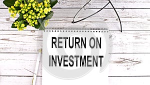 RETURN ON INVESTMENT text concept write on notebook on wooden background
