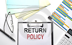 RETURN POLICY text on paper sheet with chart,color paper and calculator
