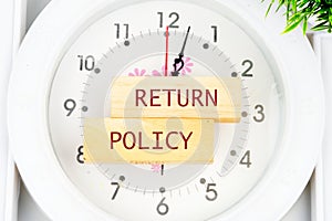 Return Policy written on the wooden blocks on the clock with hands