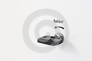 Return text written in french on a laundromat meter and black plastic retour key isolated on white metal case photo