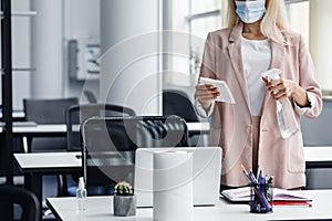 Return to work, workplace hygiene and new normal. Blond woman in business suit in protective mask with paper towel and