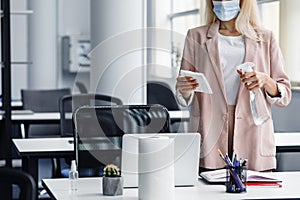 Return to work, workplace hygiene and new normal. Blond woman in business suit in protective mask with paper towel and photo