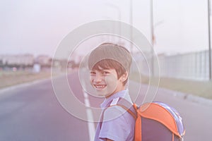 Returning to school concept, portrait of happy boy with backpack, school child waiting for school bus, primary school student, on
