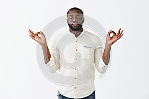 Reuniting with anture through meditation. Calm good-looking african american male in white casual shirt, raising hands