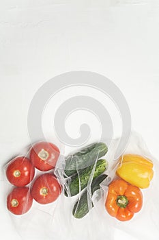 Reusable bags with, fresh vegetables tomatoes, cucumbers, bell peppers over white background