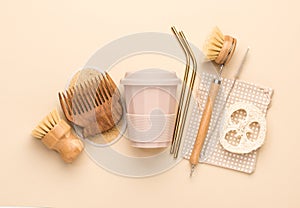 Reusable bathroom and kitchen items on a beige background. Natural cleaning brushes, Luffa scrubber, metal straws and a glass for