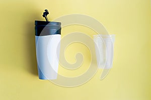 Reusable black and white takeaway coffee cup with disposable plastic cups isolated on yellow background