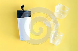 Reusable black and white takeaway coffee cup with three disposable crumpled plastic cups isolated on yellow background