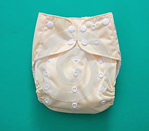 Reusable cloth baby diaper. Eco friendly nappy yellow color on green background