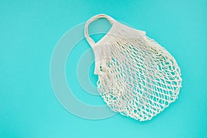 Reusable cotton net bag for shopping and food storage on mint background with copy space