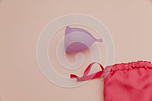 Reusable pastel purple menstrual cup on a pink background. Eco-friendly way of women's hygiene concept