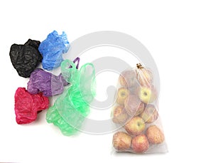 Reusable recycled mesh grocery bag full of apples and heap of standard plastic bags, on white background, zero waste and conscious