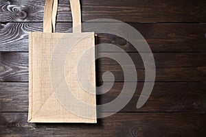 Reusable shopping bag, natural textile fiber, blank eco hessian or jute sack on brown wooden background