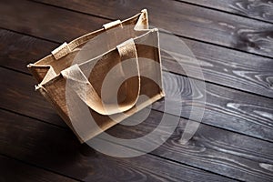 Reusable shopping bag, natural textile fiber, eco hessian or jute sack on brown wooden table
