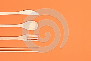 Reusable wooden cutlery. Eco friendly fork, knife, spoon on an orange background. Zero waste concept.