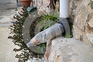 Reuse of an old plastic bottle to lengthen downspout close up