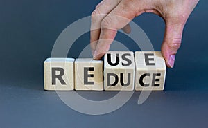 Reuse or reduce symbol. Businessman turns wooden cubes and changes the words reduce to reuse. Beautiful grey background, copy