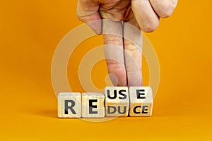 Reuse or reduce symbol. Businessman turns wooden cubes and changes the words reduce to reuse. Beautiful orange background, copy