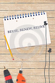 Reuse, renew, relive against tools and notepad on wooden background