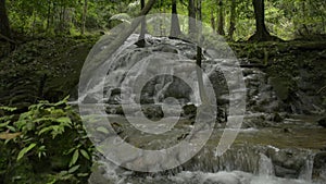 Reveal lifting shot fresh water rapids flows from cascade under sunshine in the jungle.