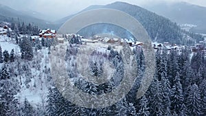 Revealing aerial of inhabited locality in the mountains on winter. Mountain village buildings on snowy hill slopes