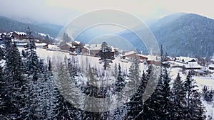 Revealing aerial of inhabited locality in the mountains on winter. Mountain village buildings on snowy hill slopes