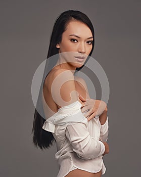 Revealling beauty. Studio shot of a beautiful woman in lingerie against a gray background.