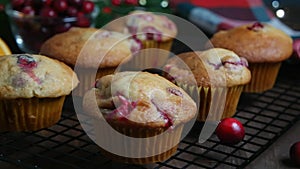 Revers dolly shot with homemade cranberry orange muffins on cooling rack, Christmas decoration on background