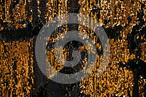 Reversible iridescent sequin fabric. Black and gold abstract glitter background. Festive double sided chameleon textile