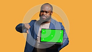 Reviewer shows thumbs down sign gesturing holding green screen laptop