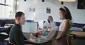 Reviewing two colleagues comparing data charts in co-working office, with laptop computers