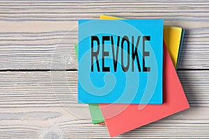 REVOKE - word on note paper on wooden light background