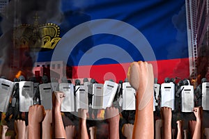 Revolt fighting concept - protest in Liechtenstein on flag background, police guards stand against the protestors crowd -