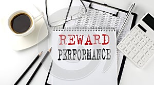 REWARD PERFORMANCE text on the paper with calculator, notepad, coffee ,pen with graph
