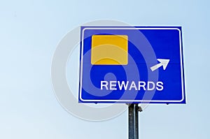 Rewards Blue Road Sign Against Sky