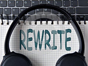 REWRITE -word on white notepad with keyboard and headphone background