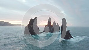 Reynisdrangar rocks at Reynisfjara Beach next to Vik i Myrdal at South Iceland. Aerial drone shot flying over a cliff.