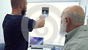 Rheumatologist show radiogram to a mature man